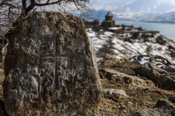 Akdamar Adası'ndaki haç kabartmalı tarihi mezar taşı, arka plandaki Akdamar Kilisesi ve Van Gölü ile eşsiz kültür mirası