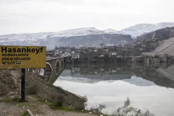 Batman Hasankeyf'te karla kaplı tarihi yerleşim, Dicle Nehri, köprü ve kayalık dağ manzarası.