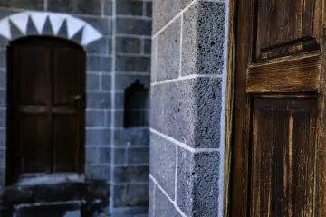 Diyarbakır’daki Cemil Paşa Konağı’nın tarihi mimarisini yansıtan taş duvar ve ahşap kapı detayı. Geleneksel yapı dokusu, taş işçiliği ve ahşap mimari unsurlar ön plandadır.