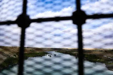 Malabadi Köprüsü korkulukları arasından görülen Dicle Nehri ve dramatik gökyüzünü yansıtan yaratıcı kompozisyon.
