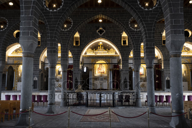Diyarbakır Meryem Ana Süryani Kadim Kilisesi'nin siyah taş kemerler, sütunlar ve ikonalarla bezeli tarihi iç mekânı.