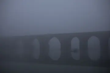 Diyarbakır On Gözlü Köprü'nün yoğun sis altında belirginleşen tarihi kemerleri ve atmosferik görünümü.