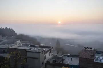 Diyarbakır Hevsel Bahçeleri ve Dicle Vadisi üzerinde sisli gün doğumu, evler ve ağaçlık alanlarla etkileyici sabah manzarası.