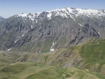 Hakkâri Cilo Dağları'nda karlı yüksek zirveler, sarp kayalık yamaçlar ve yeşil dağ manzarası.