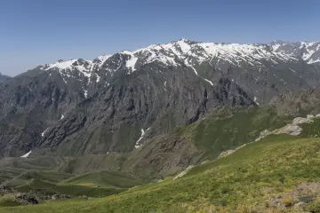 Hakkâri Cilo-Sat Dağları'nda yeşil yamaçlar, sarp kayalıklar ve karla kaplı yüksek zirveler.