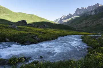 Hakkâri Cilo-Sat Dağları'nda yemyeşil vadi, berrak akarsu ve sarp kayalıklarla çevrili etkileyici dağ manzarası.