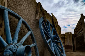 Harran kerpiç evinde bulunan geleneksel ahşap araba tekerlekleri ve tarihi mimari detayları gösteren otantik görünüm.