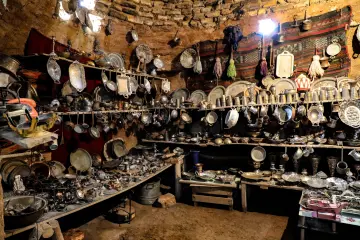 Harran Kümbet Evi'nin iç mekanında geleneksel bakır kaplar, metal eşyalar ve dokumalar.