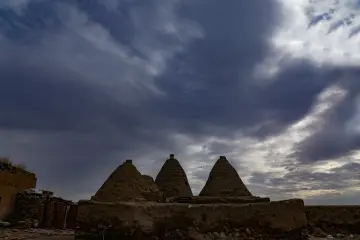 Harran Kümbet Evleri ve konik kubbelerin dramatik bulutlu gökyüzü altında etkileyici görünümü.