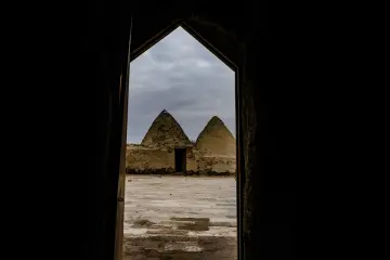 Harran'ın geleneksel kümbet evleri, tarihi bir kapıdan bakışla özgün mimarisi ve avlusuyla görüntüleniyor.