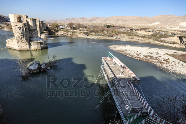 Hasankeyf'te eski bir yapının yıpranmış penceresinden dışarı bakan genç bir buzağı. Tuğla duvar, ahşap pencere ve hayvanın meraklı bakışı, tarihi çevre ile kırsal yaşamın iç içe geçtiği doğal bir sahne oluşturuyor.