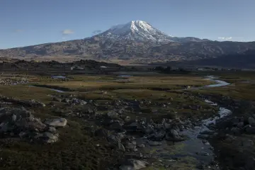 Iğdır çevresinden Ağrı Dağı'nın karlı zirvesi, kayalık arazi ve dağ eteklerindeki akarsu manzarası.
