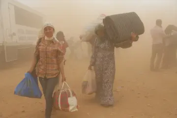 İŞİD saldırısından kaçan Kobani’liler, Suruç’a geçmek için mayınlı bölgeden sınırın karşı tarafına geçiyor. Gözleri kör eden kum  fırtınası  da bebekler ve çocuklar için de zorlu bir göç yolculuğa dönüşüyor.