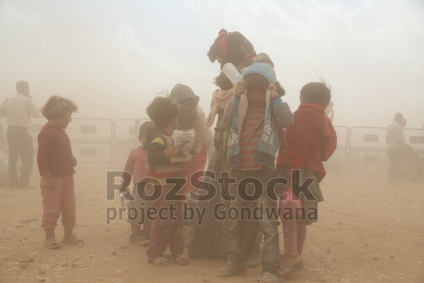 İŞİD saldırısından kaçan Kobani’liler, Suruç’a geçmek için mayınlı bölgeden sınırın karşı tarafına geçiyor. Gözleri kör eden kum  fırtınası  da bebekler ve çocuklar için de zorlu bir göç yolculuğa dönüşüyor.
