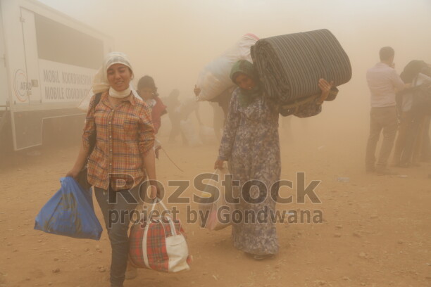 İŞİD saldırısından kaçan Kobani’liler, Suruç’a geçmek için mayınlı bölgeden sınırın karşı tarafına geçiyor. Gözleri kör eden kum  fırtınası  da bebekler ve çocuklar için de zorlu bir göç yolculuğa dönüşüyor.