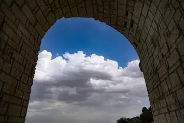 Malabadi Köprüsü kemerinden görülen mavi gökyüzü ve bulutlar, Diyarbakır'ın tarihi mimarisini estetik bir kadrajla sunuyor.