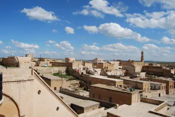 Mardin'in tarihi taş evleri, geleneksel mimarisi ve teraslı şehir dokusunun gökyüzü altında panoramik görünümü.