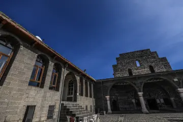 Meryem Ana Süryani Kadim Kilisesi'nin taş duvarlı avlusu, kemerli revakları ve tarihi mimari detayları.