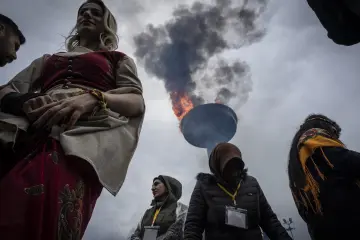 21 Mart 2025 Diyarbakır Amed Newrozunda geleneksel kıyafetli kadınlar ve yükselen Newroz ateşi eşliğinde özgürlük coşkusu.