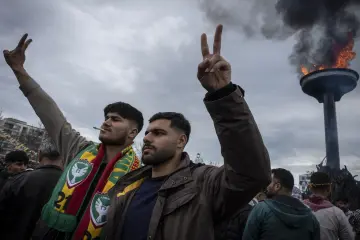 21 Mart 2025 Diyarbakır Amed Newrozunda Amedspor atkılı katılımcılar zafer işareti yaparken Newroz ateşi yanıyor.