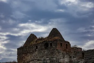 Şanlıurfa Harran'daki tarihi kümbet evleri ve geleneksel taş mimarisini bulutlu gökyüzü