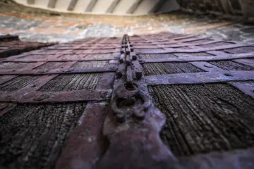 Tarihi ahşap kapıda demir kuşaklar, metal çiviler ve yıpranmış ahşap dokusunun yakın plan görünümü.