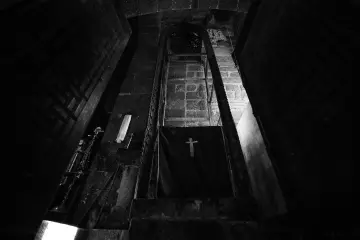 Tarihi kilisenin iç mekanında haç işlemeli örtü, taş duvarlar ve ahşap kapılarla oluşan etkileyici görünüm.
