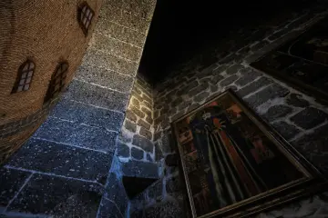 Tarihi kilisenin taş duvarında dini tasvir, tuğla kubbe ve geleneksel mimari detayların birlikte görünümü.