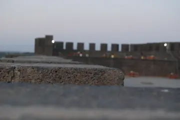 Tarihi surların bulanık arka planda görüldüğü, taş duvar dokusuna odaklanan etkileyici mimari görüntü.