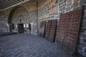 Tarihi Süryani kilisesinde bazalt taş duvarlar, kemerli mimari ve geleneksel ahşap kapılar.