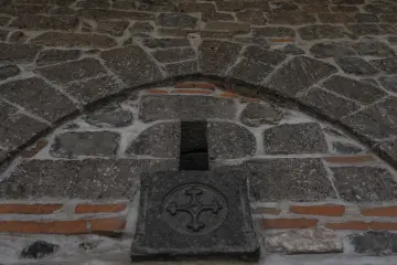 Tarihi taş duvar üzerinde dekoratif motif, küçük açıklık, kemerli bölüm ve taş işçiliği detayları.