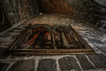 Tarihi taş duvar üzerinde iki dini figürün yer aldığı çerçeveli tasvir ve taş tuğla mimari detayları.