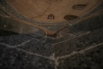 Tarihi yapının tuğla örgülü kubbesi, taş duvarları ve küçük pencereleriyle dikkat çeken iç mekan görünümü.