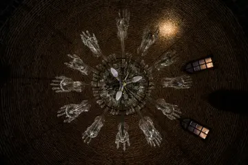 Tarihi yapının tuğla örgülü kubbesinde asılı büyük cam avize ve küçük pencereler.