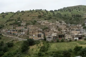 Yeşil dağ yamacında sıralanan geleneksel taş evler ve çevresindeki doğal peyzajın etkileyici görünümü.
