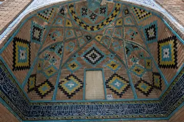 İran Yezd Ulu Camii'nde mavi çini mozaikler, geometrik motifler ve hat yazılarıyla süslü tarihi mimari detay.